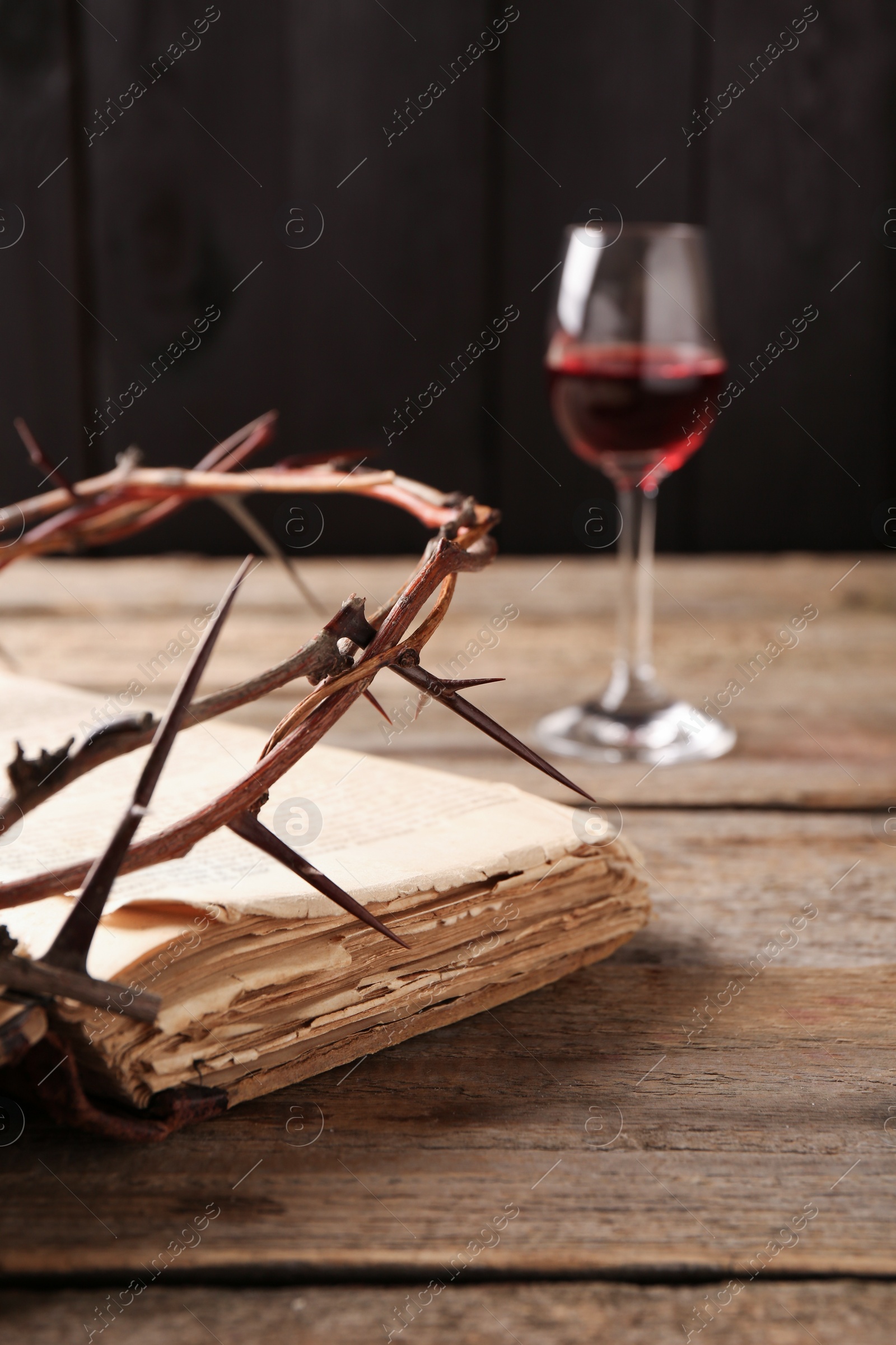 Photo of Crown of thorns, Bible and glass with wine on wooden table, selective focus