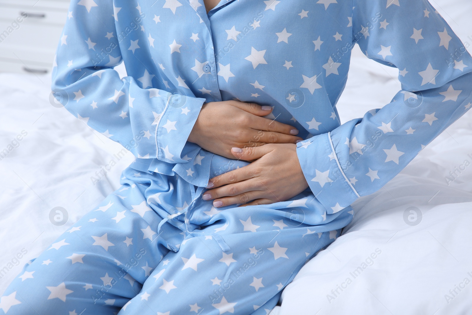 Photo of Young woman suffering from stomach ache on bed, closeup