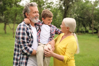 Photo of Cute little boy and grandparents spending time together in park