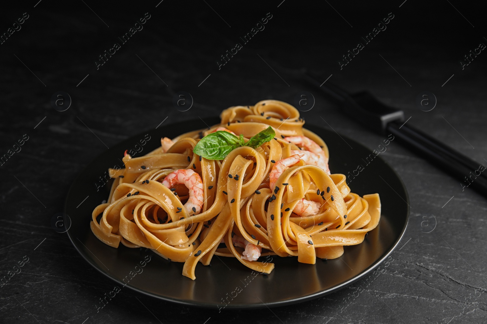 Photo of Tasty buckwheat noodles with shrimps on black table