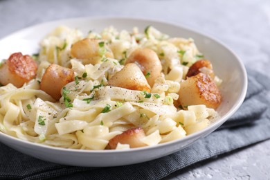 Photo of Delicious scallop pasta with spices in bowl on gray table, closeup