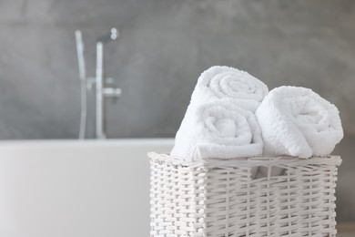 Photo of Wicker basket with fresh white towels in bathroom, closeup. Space for text