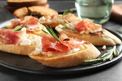 Tasty bruschettas with prosciutto and cream cheese served on table, closeup