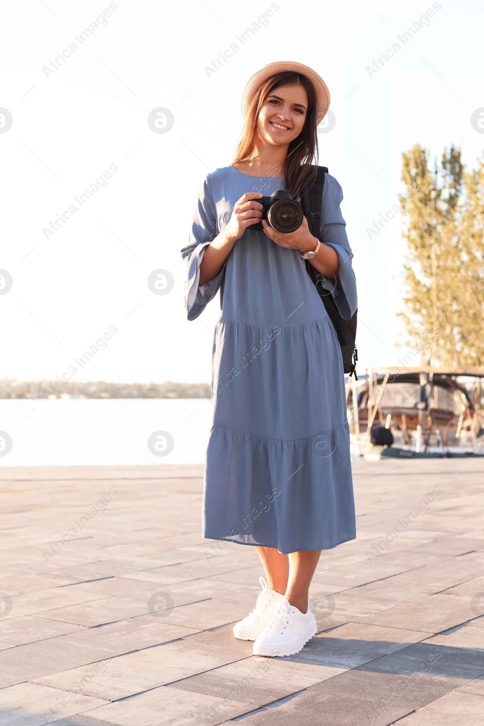 Photo of Young female photographer holding professional camera at pier