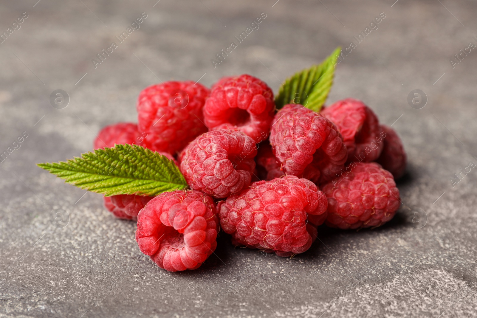 Photo of Heap of delicious ripe raspberries on stone surface, closeup