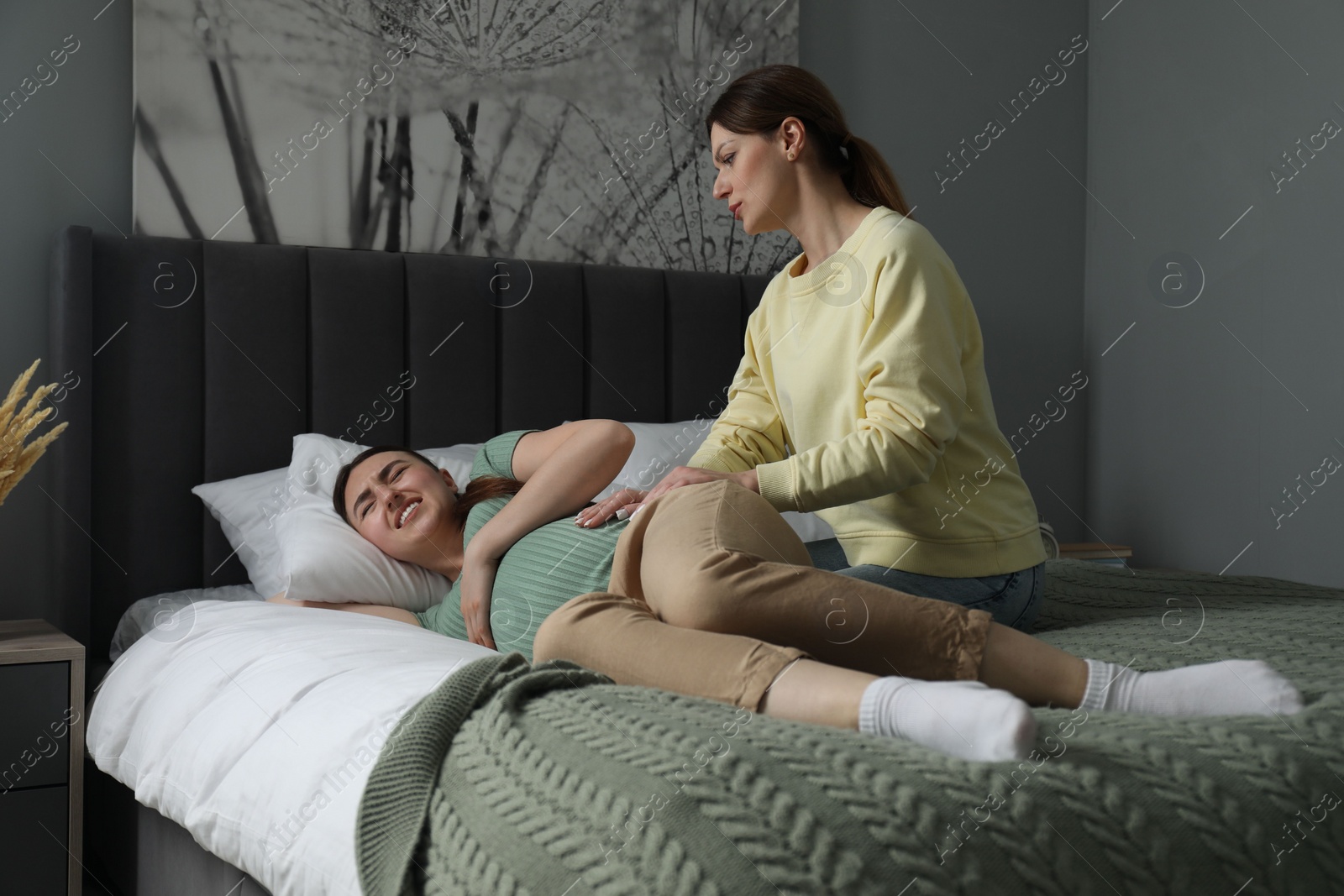 Photo of Doula taking care of pregnant woman in bedroom. Preparation for child birth