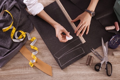 Tailor working with cloth at table in atelier, top view