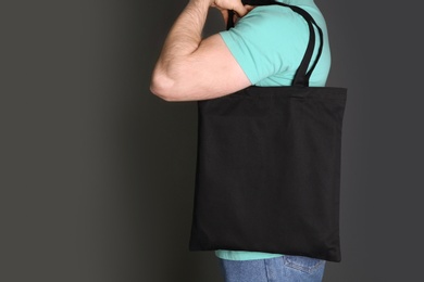 Photo of Man with cotton shopping eco bag on grey background. Mockup for design