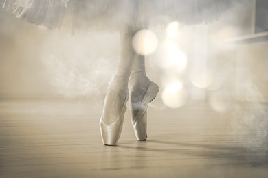 Image of Perfection in ballet. Woman dancing in pointe shoes in studio, closeup. Bokeh effect with smoke
