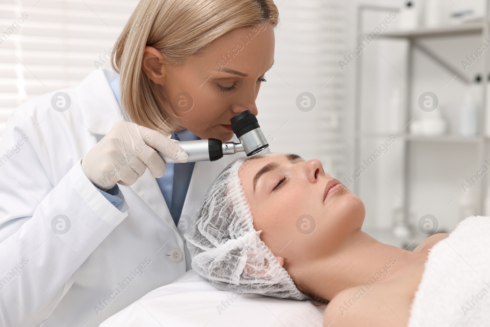 Photo of Dermatologist with dermatoscope examining patient`s face in clinic