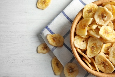 Photo of Wooden bowl with sweet banana slices on table, top view with space for text. Dried fruit as healthy snack