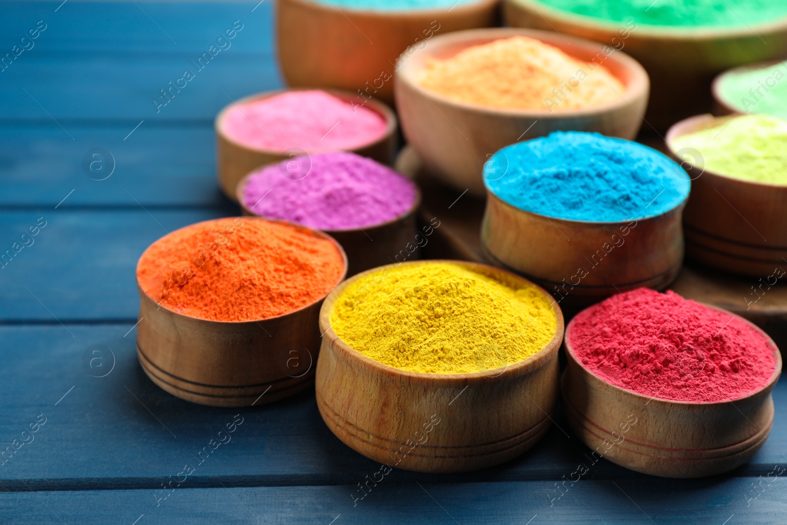 Photo of Colorful powder dyes on blue wooden background, closeup. Holi festival
