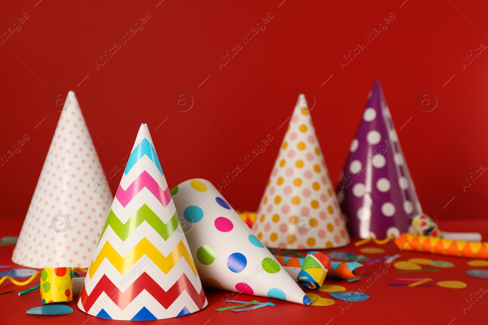 Photo of Many colorful party hats and festive items on red background