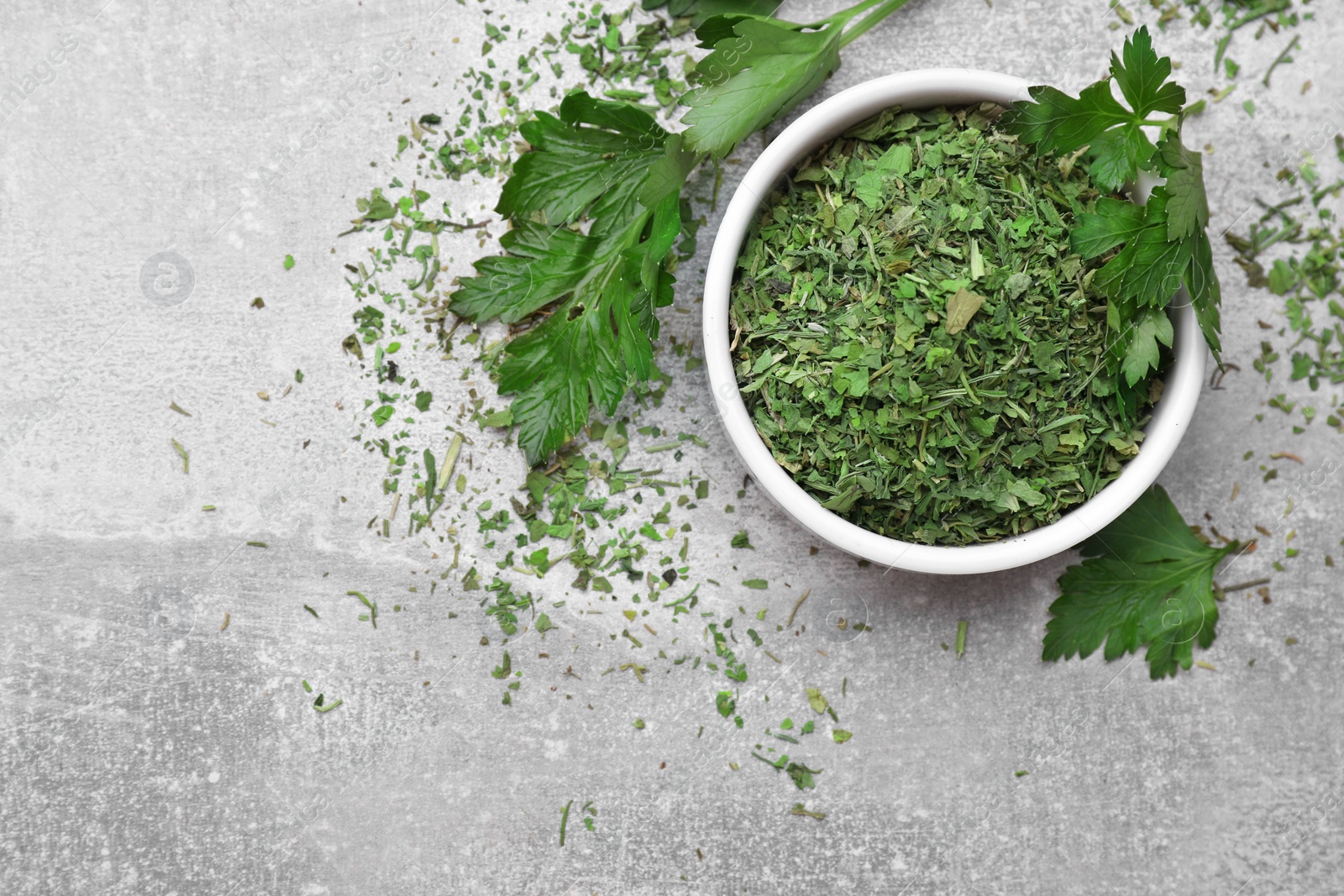 Photo of Dried parsley and fresh leaves on light grey table, flat lay. Space for text