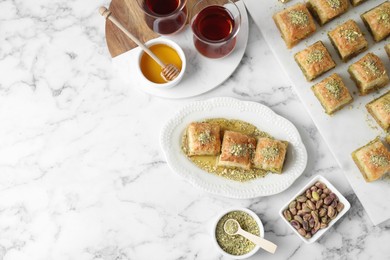 Photo of Delicious fresh baklava with chopped nuts served on white marble table, flat lay and space for text. Eastern sweets