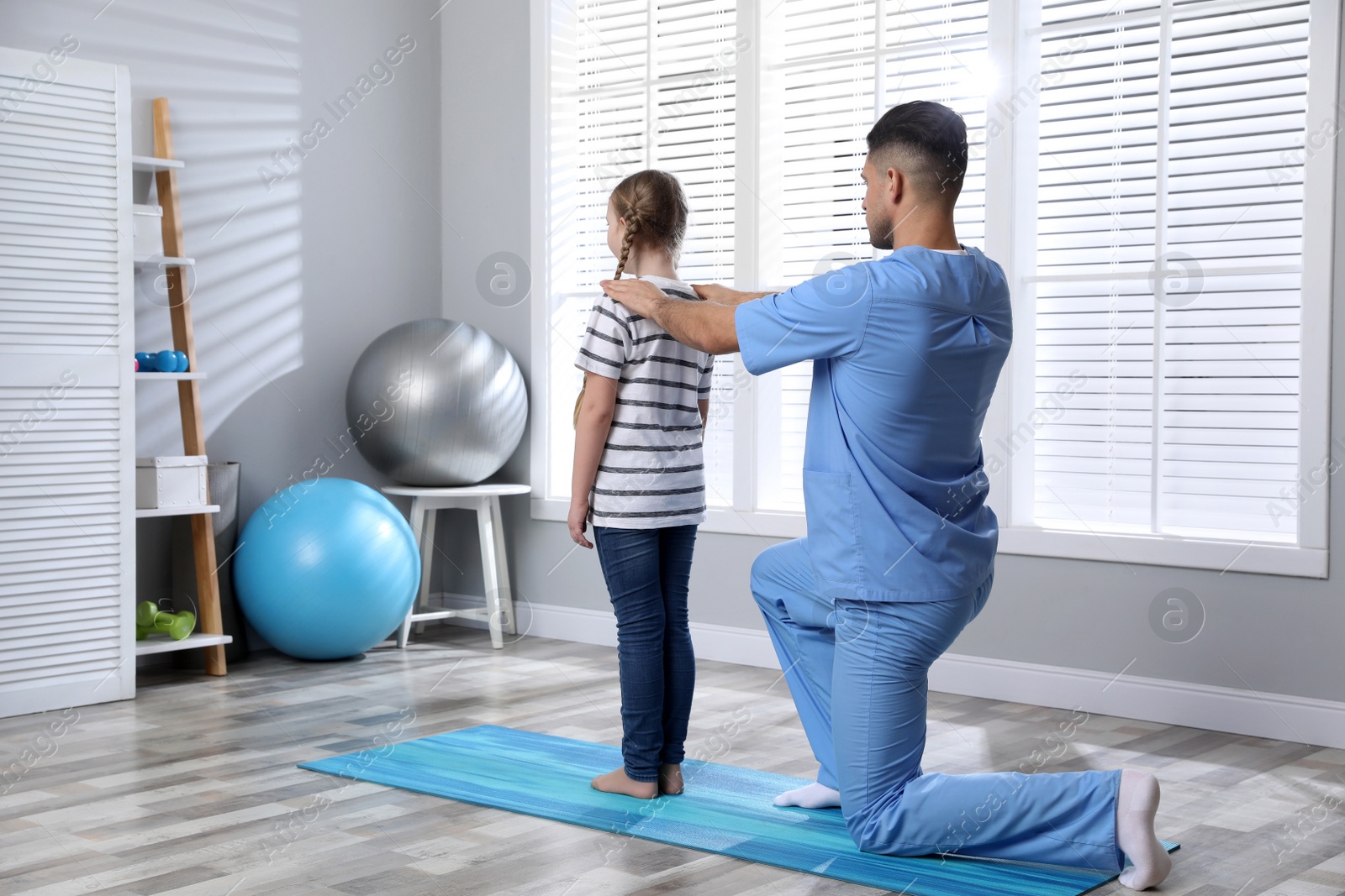 Photo of Orthopedist examining child's back in clinic. Scoliosis treatment