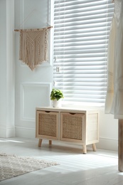 Photo of Wooden commode near window in room. Interior design