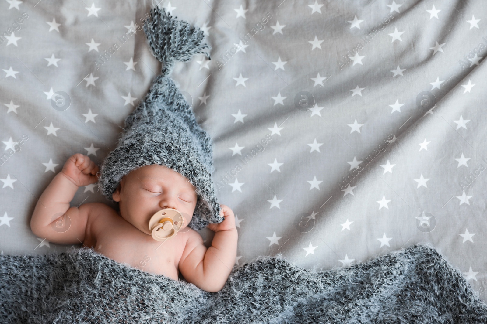 Photo of Cute newborn baby in warm hat sleeping on bed, top view. Space for text