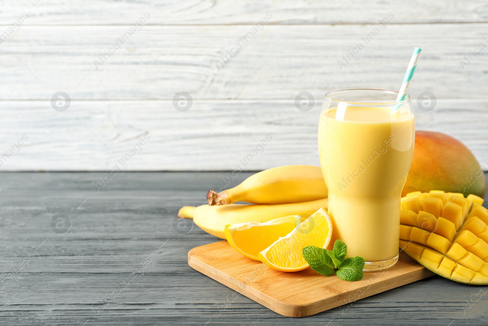 Photo of Tasty tropical drink with mango and fresh fruits on wooden table. Space for text