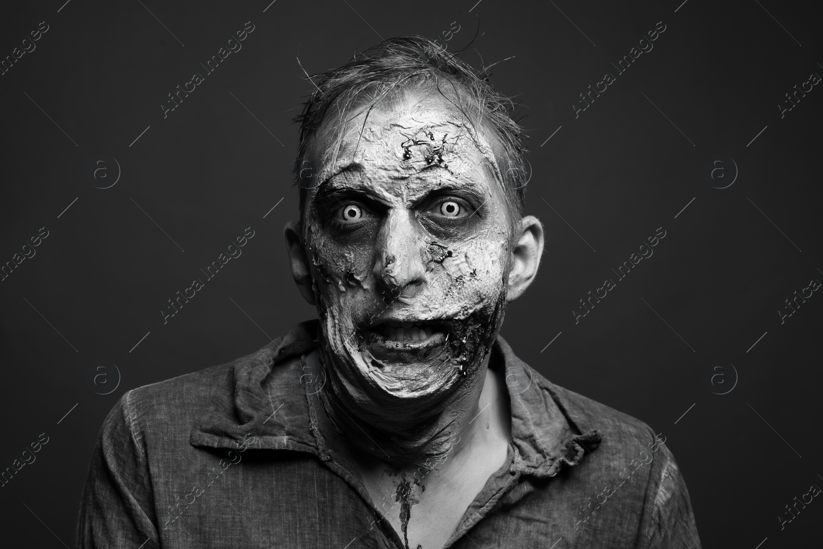 Photo of Scary zombie on dark background, black and white effect. Halloween monster