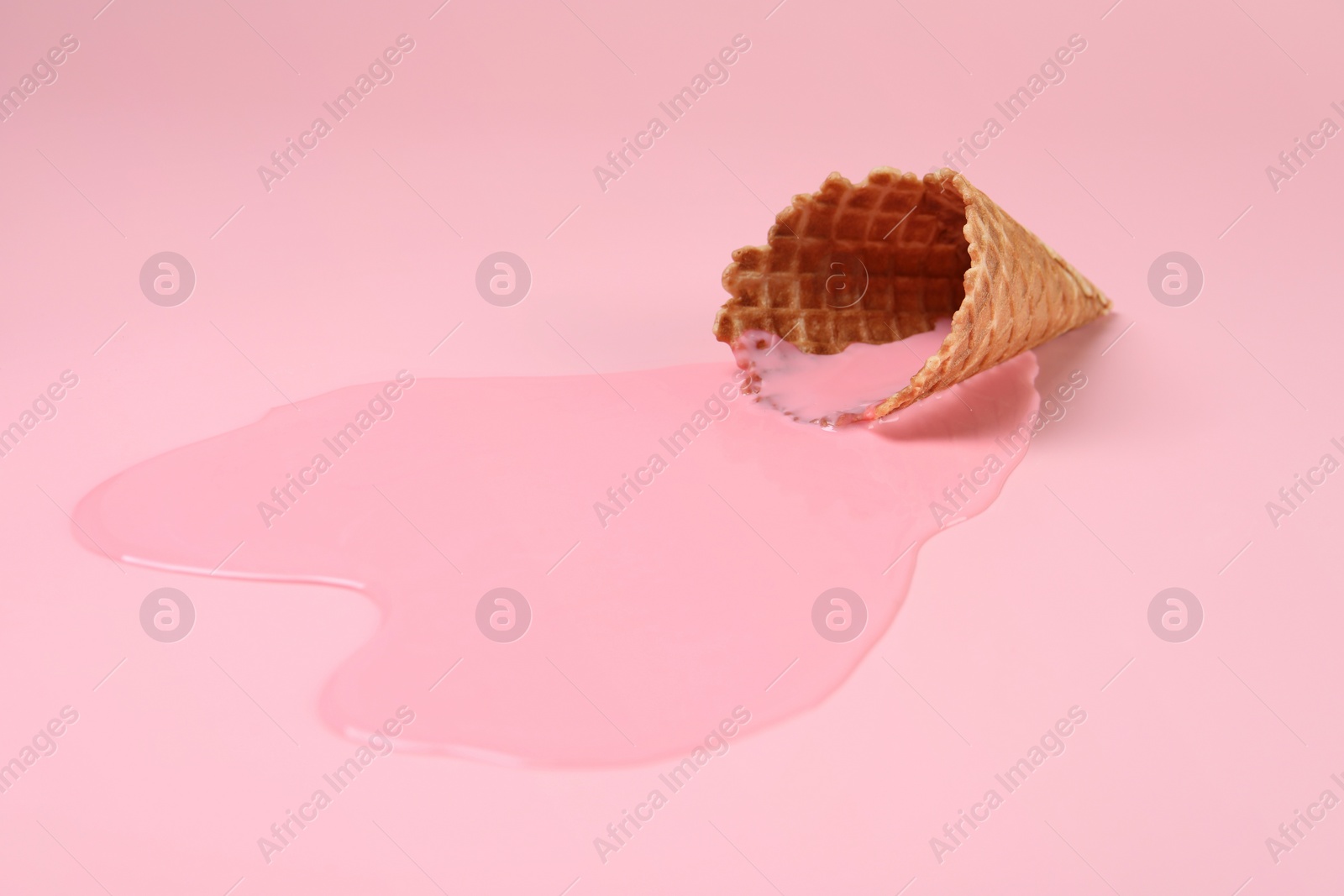 Photo of Melted ice cream and wafer cone on pink background