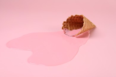 Melted ice cream and wafer cone on pink background