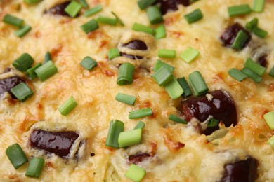 Photo of Tasty sausage casserole with green onions as background, closeup