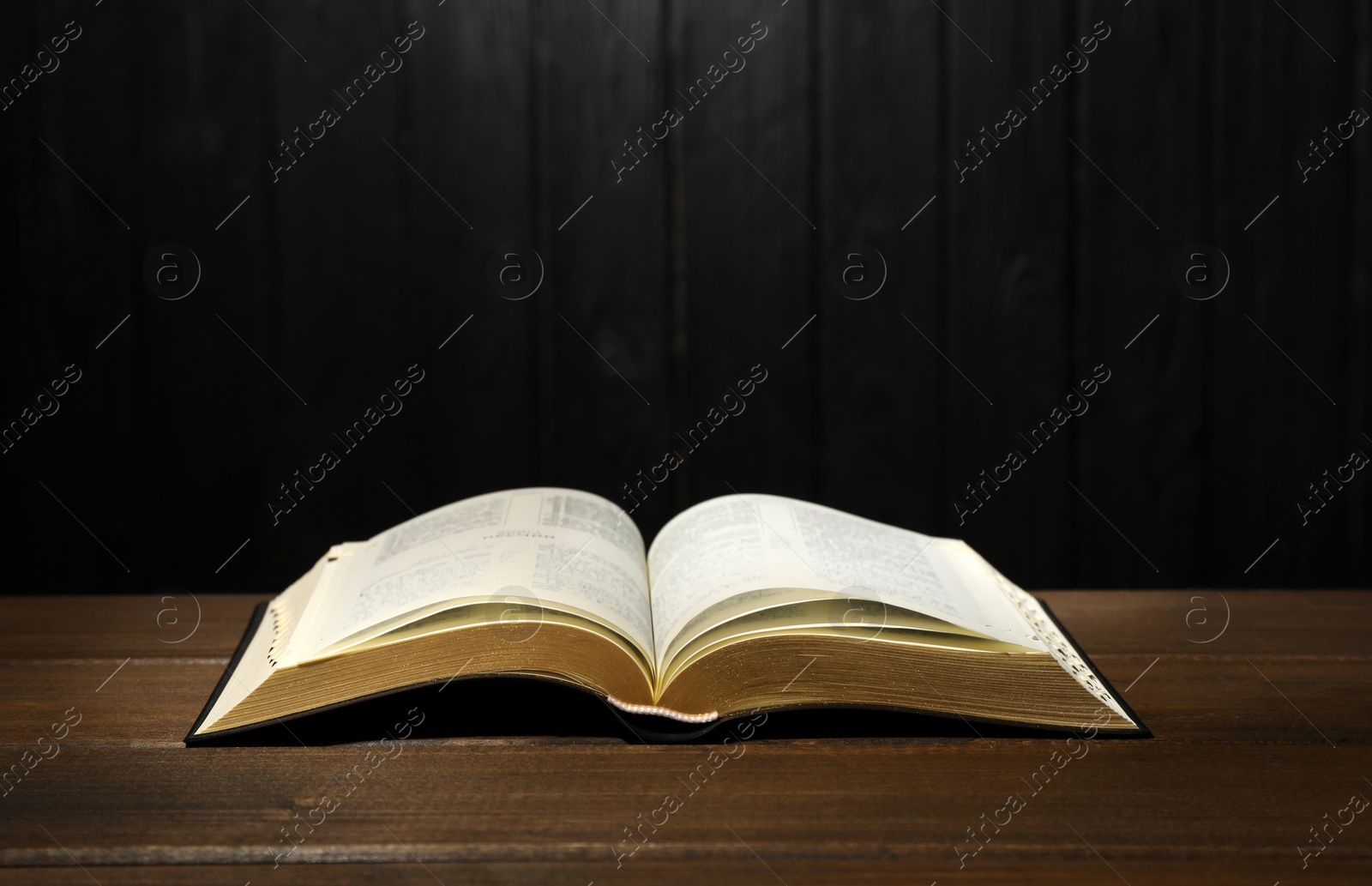 Photo of Open Bible on table against black wooden background. Christian religious book