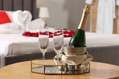 Honeymoon. Sparkling wine and glasses on wooden table in room