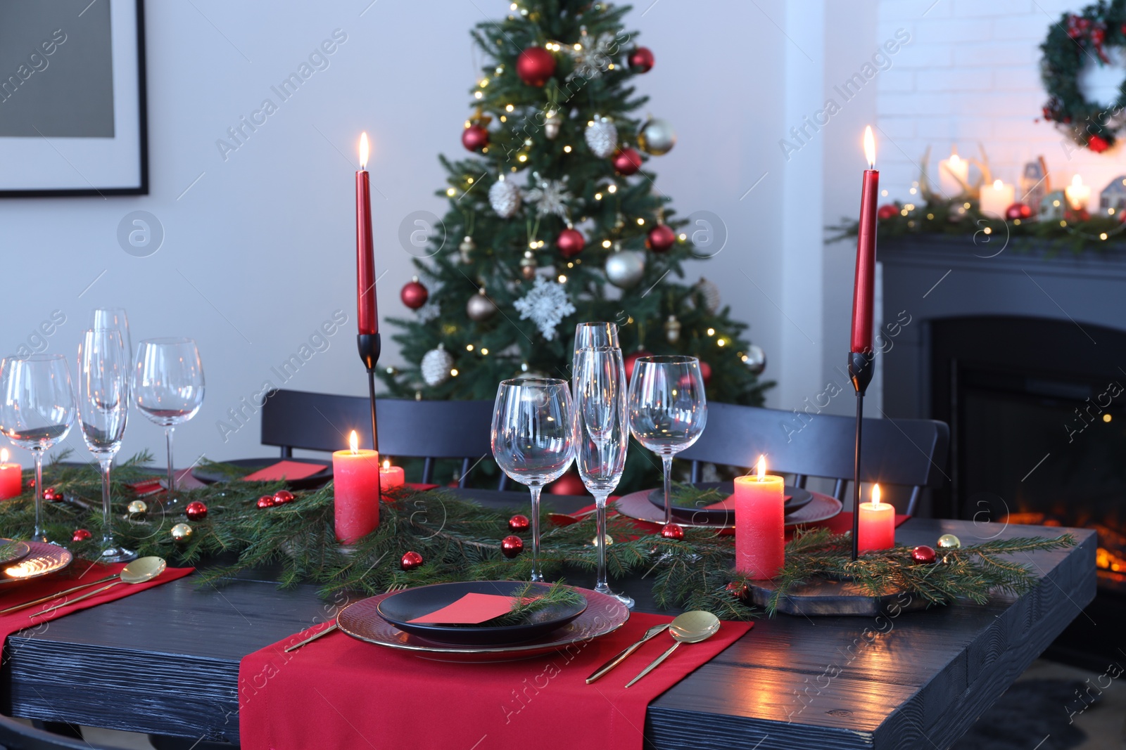 Photo of Elegant Christmas table setting with dishware and burning candles in festively decorated room