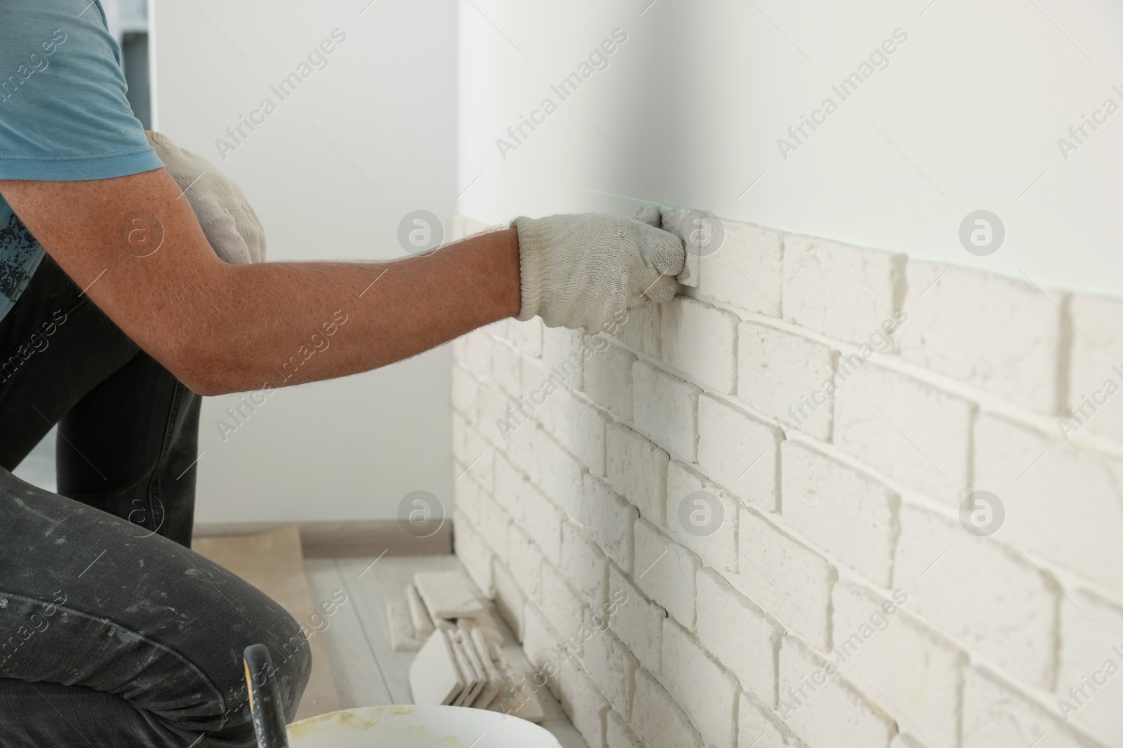 Photo of Worker installing decorative wall tiles in room, closeup