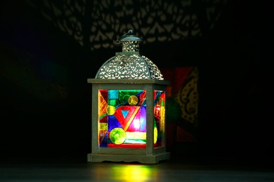 Photo of Decorative Arabic lantern on table against dark background. Space for text