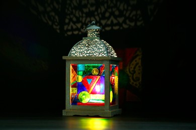 Decorative Arabic lantern on table against dark background. Space for text