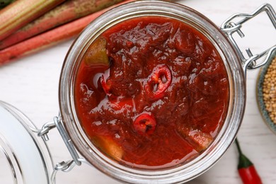 Photo of Tasty rhubarb sauce with chili pepper on white table, flat lay