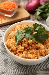 Photo of Delicious red lentils with parsley in bowl on table, closeup