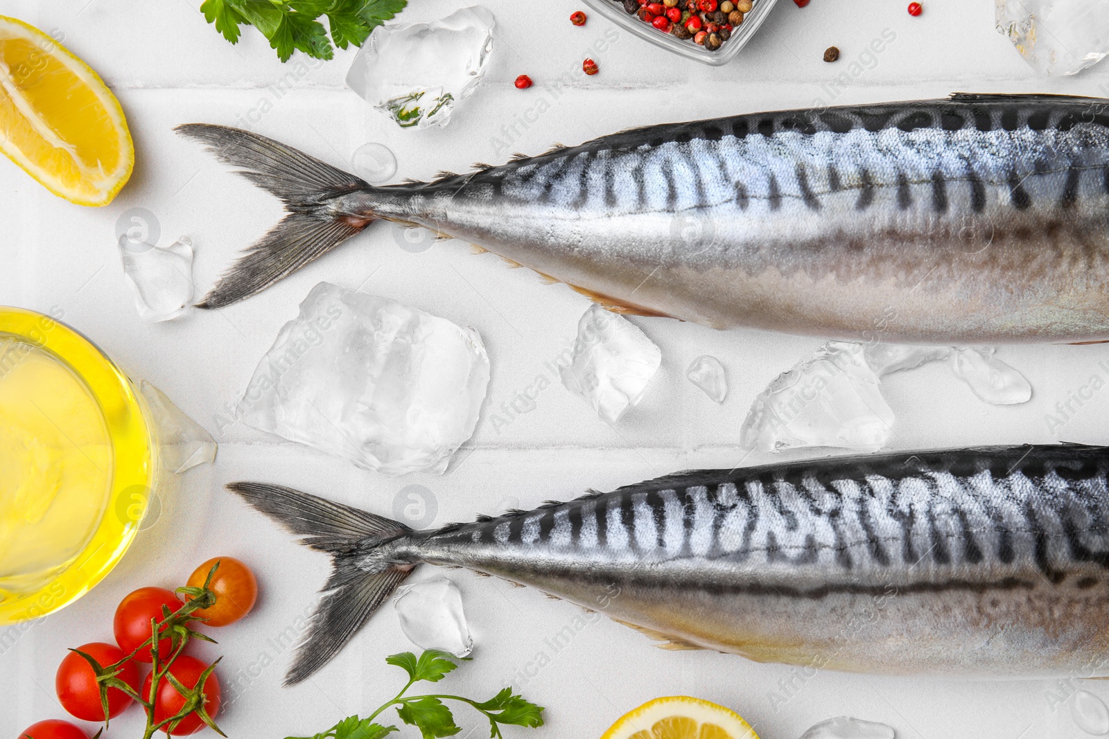 Photo of Raw mackerel, tomatoes and lemon on white table, flat lay