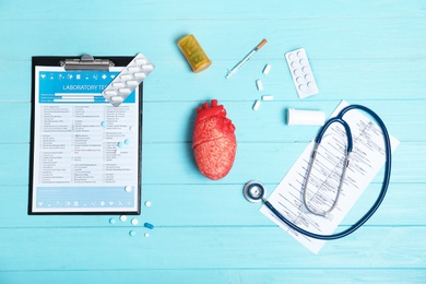 Flat lay composition with stethoscope and pills on wooden background. Cardiology service