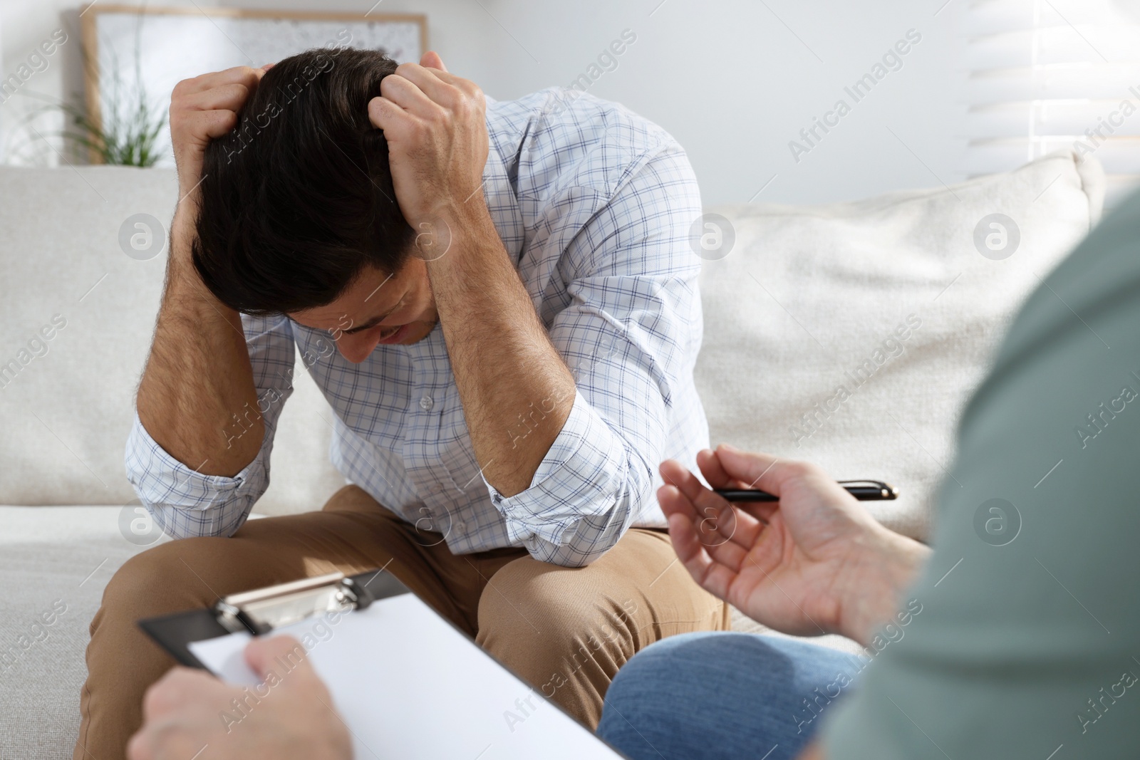 Photo of Unhappy man having session with his therapist indoors