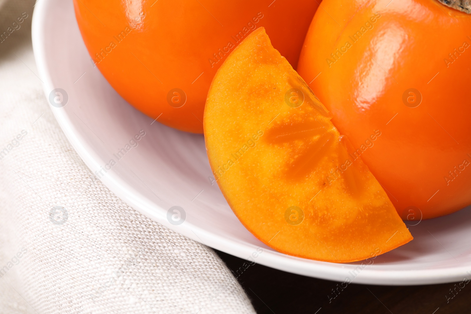 Photo of Delicious ripe persimmons in bowl on table, closeup