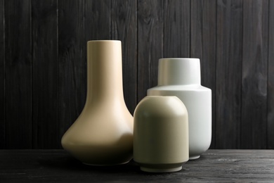 Stylish ceramic vases on black wooden table