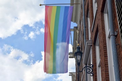 Photo of Bright rainbow LGBT pride flag on building facade, low angle view