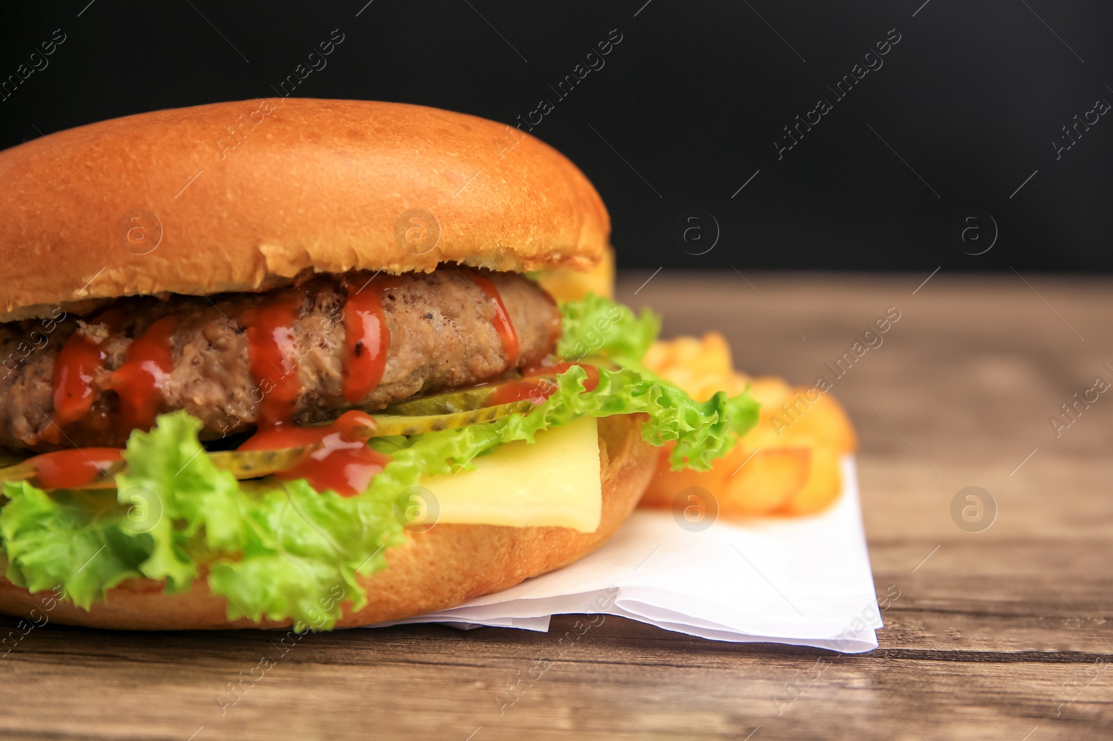 Photo of Tasty burger with patty, lettuce and cheese on wooden table, closeup. Space for text