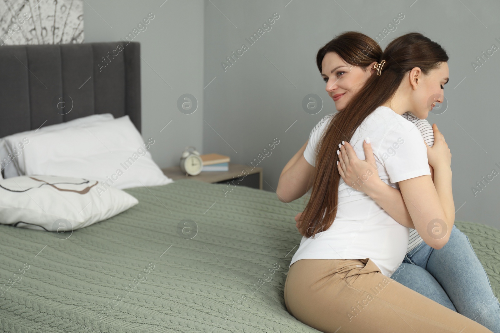 Photo of Doula hugging pregnant woman in bedroom. Preparation for child birth