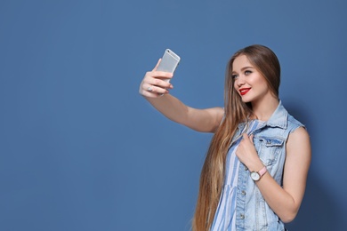 Photo of Attractive young woman taking selfie on color background