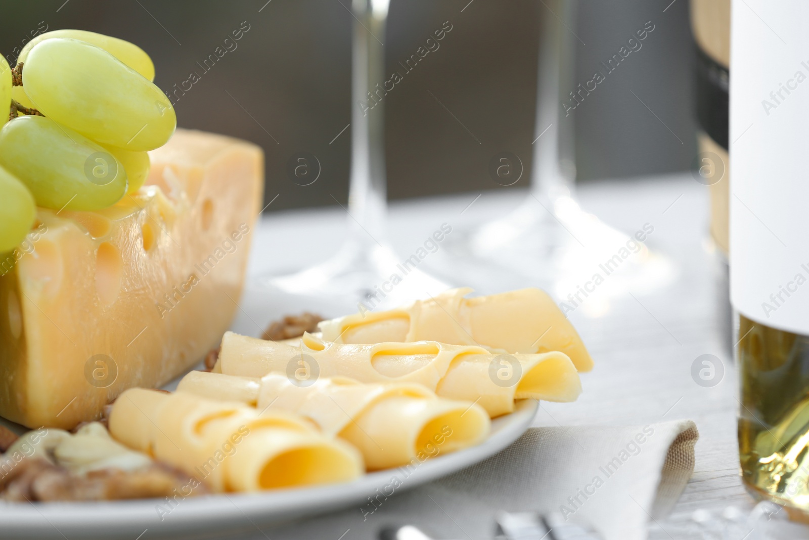 Photo of Composition with bottle of wine and snacks on table outdoors, closeup