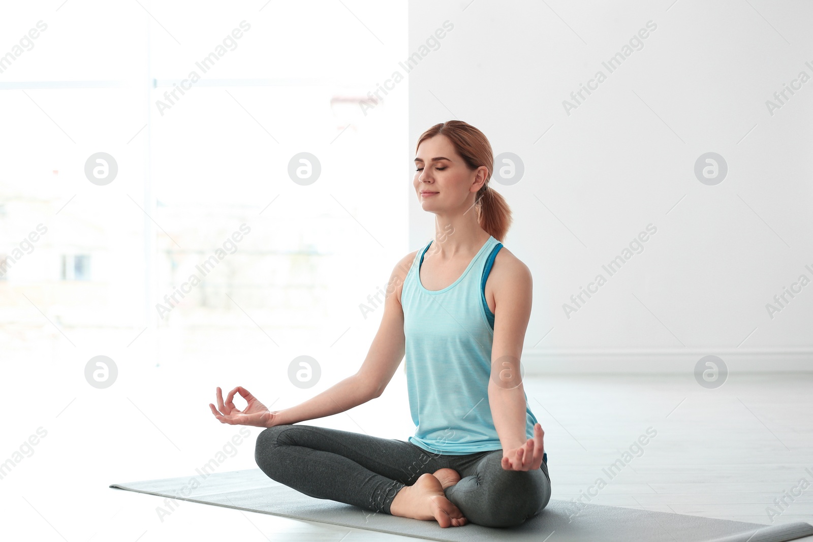 Photo of Beautiful woman meditating on floor indoors. Zen yoga