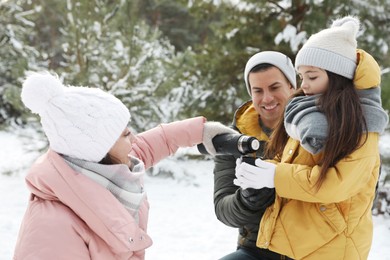 Happy family with thermos outdoors on winter day. Christmas vacation
