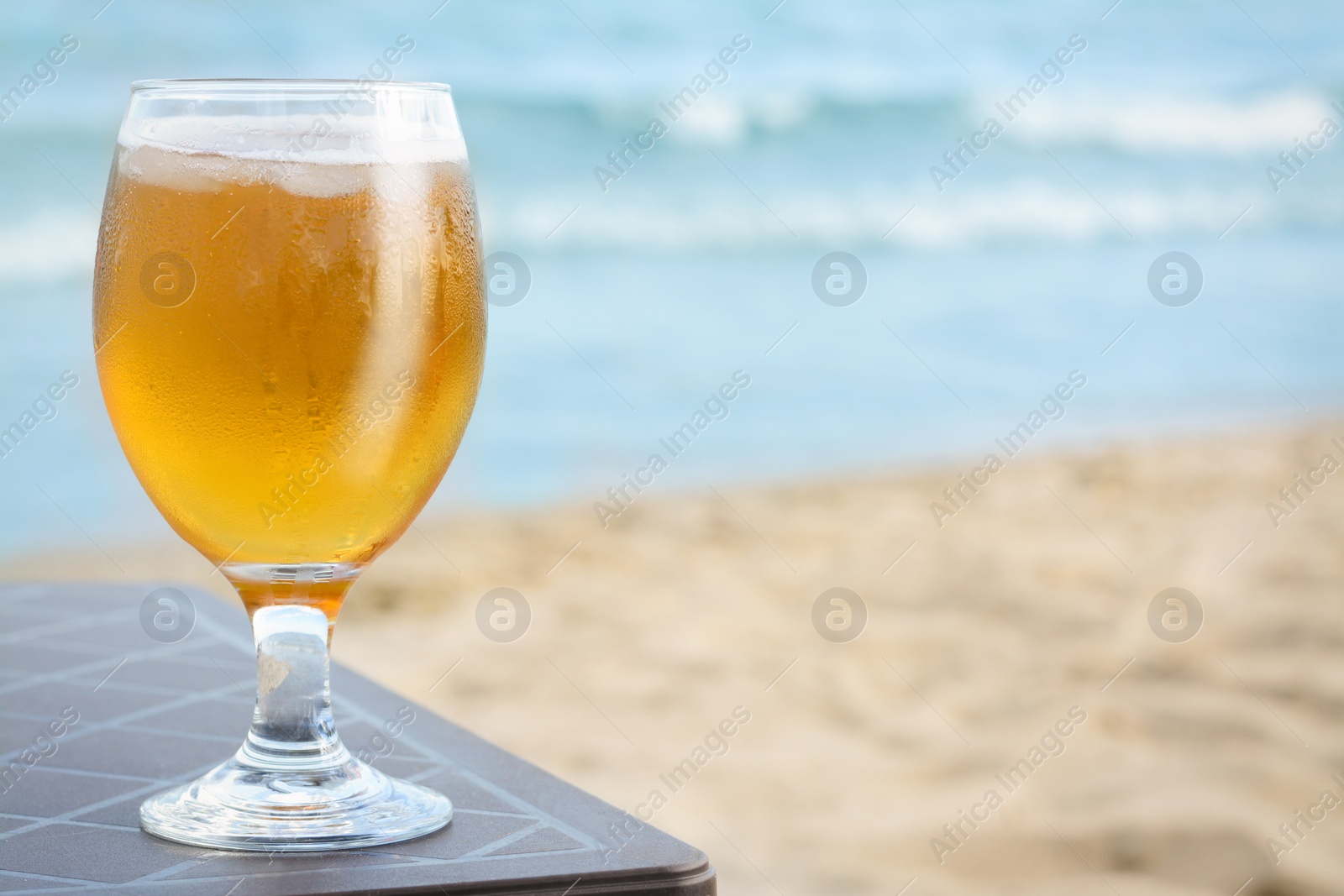 Photo of Cold beer in glass on beach. Space for text