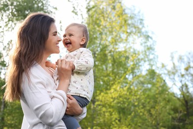 Photo of Happy mother with her cute baby in park on sunny day, space for text