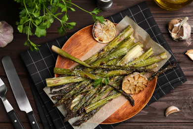 Oven baked asparagus served with garlic, lemon and parsley on wooden table, flat lay